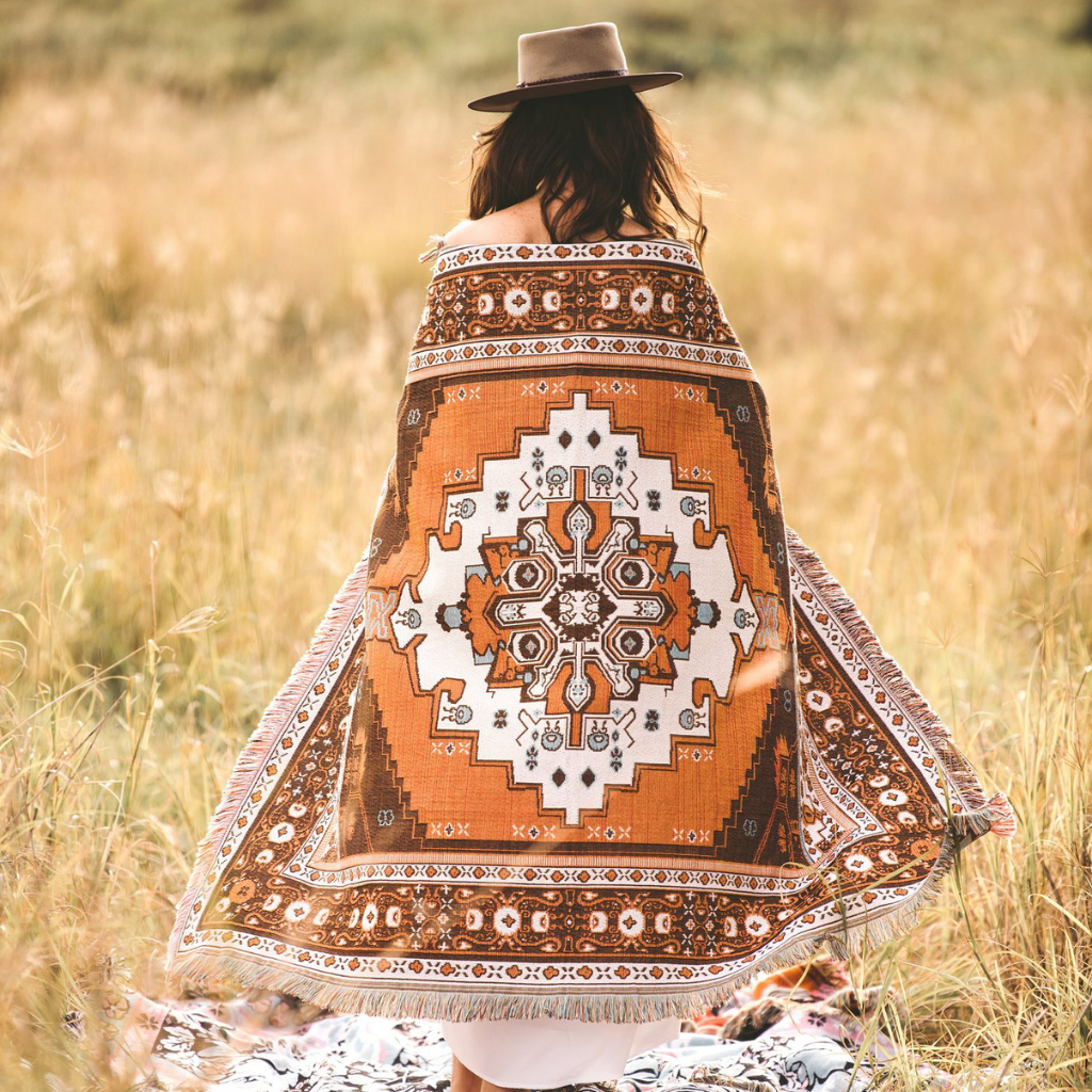 Woman standing in field with Hendeer Norwegian Wood picnic rug around her.